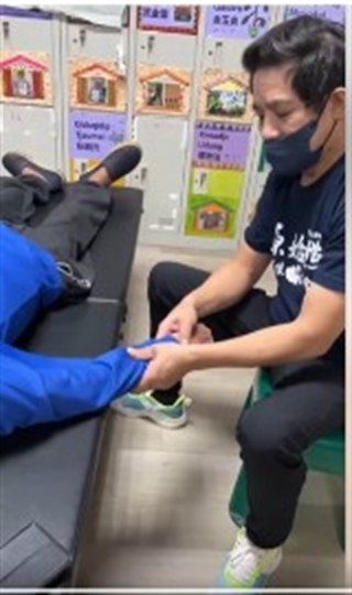一名穿著黑色上衣的工作人員，在室內活動現場協助坐臥者。