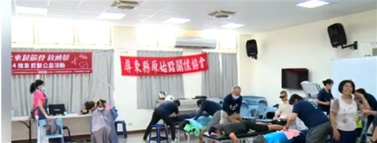 室內公益活動現場，多名工作人員與民眾在活動空間內交流，背景可見協會與合作單位布條。